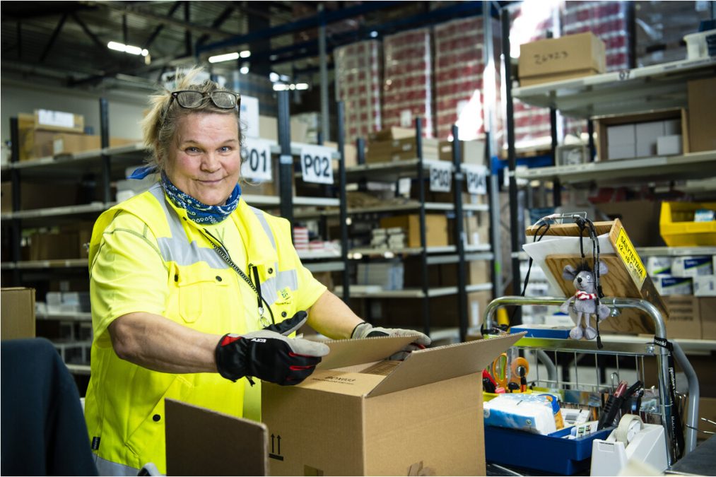 Staran logistiikkakeskuksen työntekijä varastossa pakkaamassa tuotteita pahvilaatikkoon. Kuva: Veikko Somerpuro