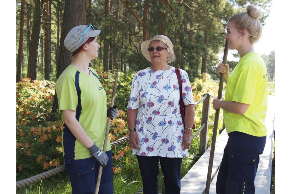 Kaksi Staran kesätyöntekijää juttelemassa Rhododendron-puistossa kaupunkilaisen kanssa. Kuva: Janne Saavalainen