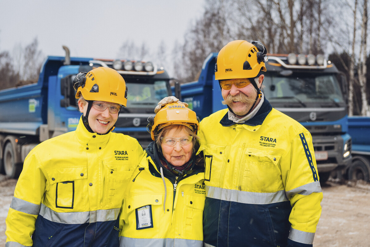 Kolmen staralaisen tiimi suojavaatteissa kuorma-autojen edessä.