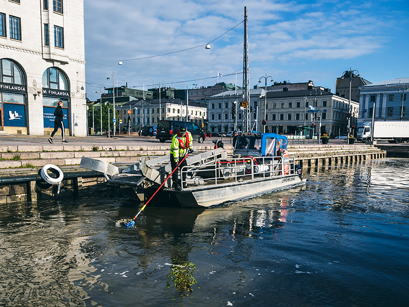 Staran työntekijä kerää roskia Lippo-aluksella Kauppatorin rannassa.