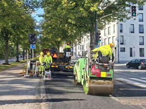 Työntekijöitä asfalttityömaalla käyttämässä jyrää ja tärylätkää